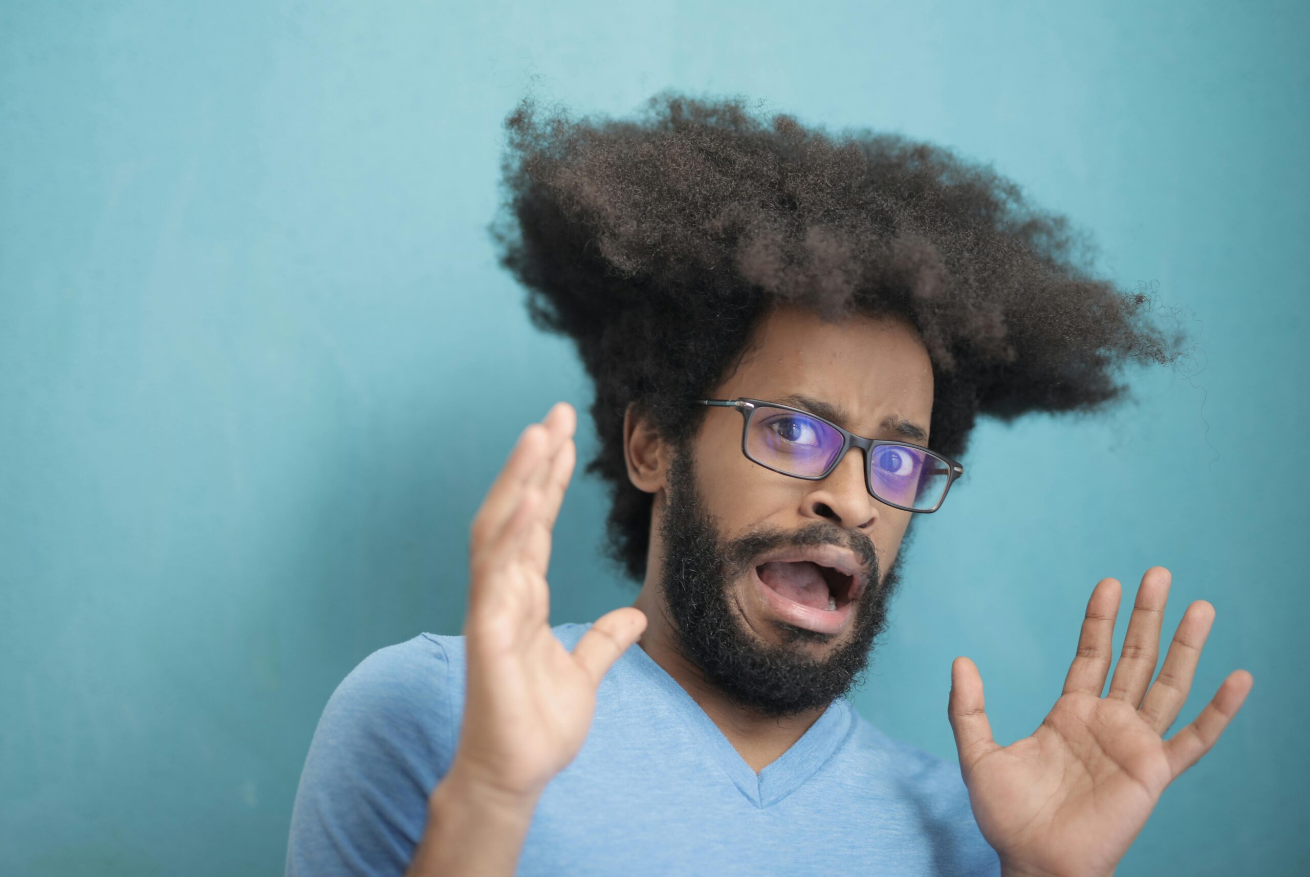 a man with curly hair and glasses with his mouth open